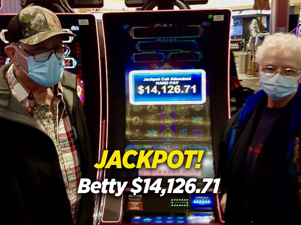 Two people wearing masks in front of a slot machine.