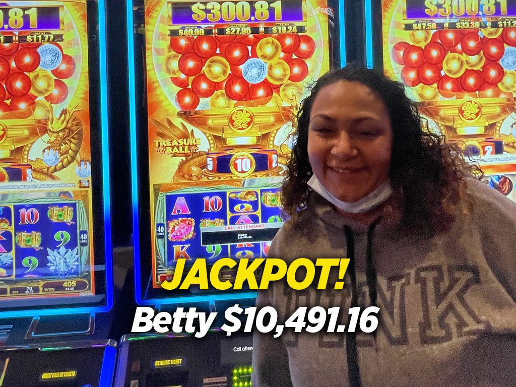 A woman standing in front of a slot machine with the words jackpot betty.