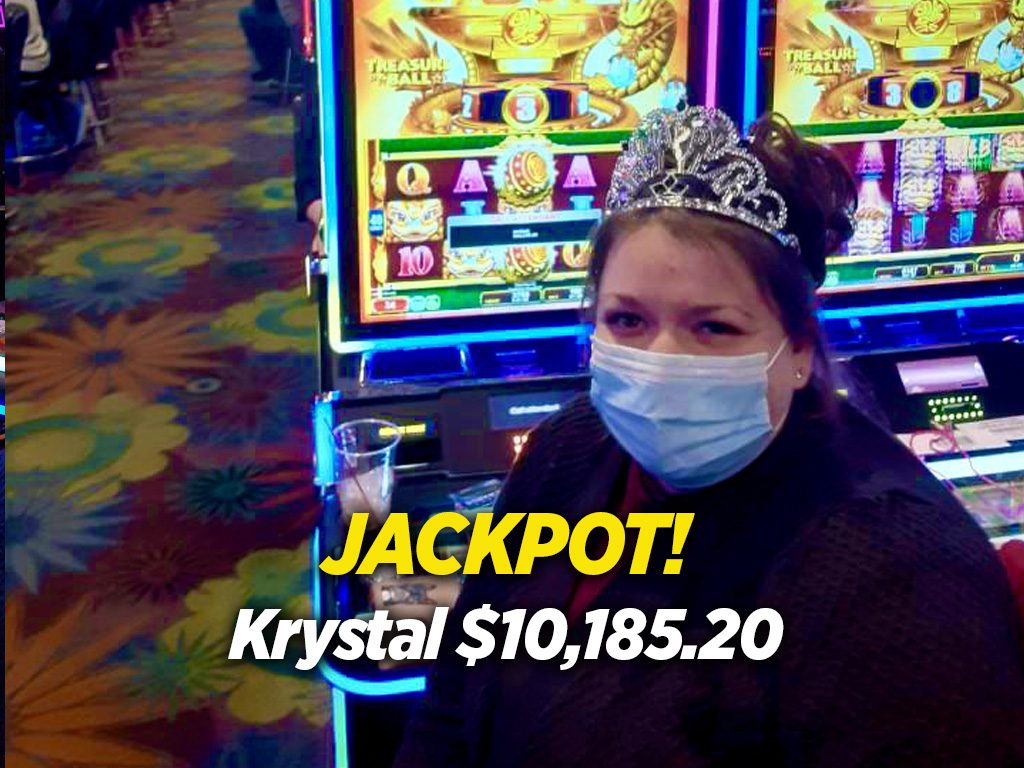 A woman wearing a mask in front of a slot machine.