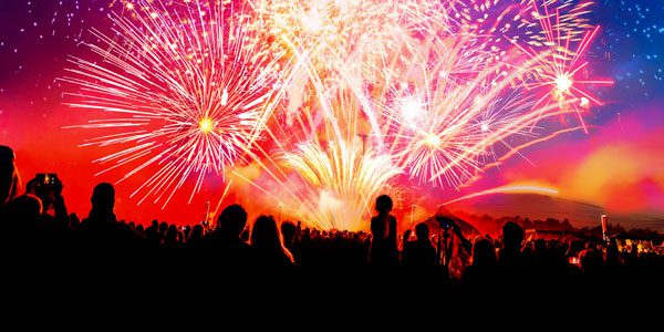 A crowd of people watching fireworks at night.