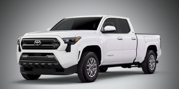 A white Toyota pickup truck is parked against a plain gray background, shown from a front-side angle.