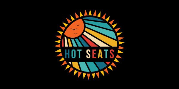 A circular sunburst graphic with bold lines and colors, featuring the words "HOT SEATS" across the center in capital letters, on a black background.