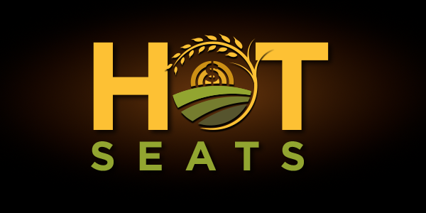 Logo for “Hot Seats” with stylized text; the “O” features a farm landscape with crops, a barn, and a golden wheat motif.