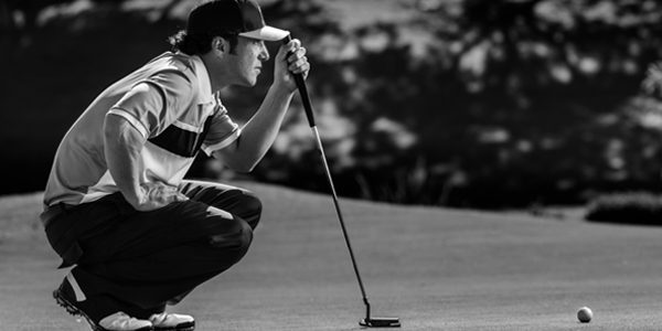 A black and white photo of a golfer crouching down.