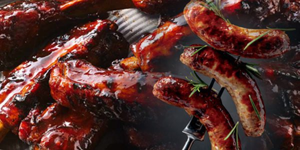 A close-up of barbecued sausages and ribs, glazed with a shiny coating of sauce and garnished with rosemary.