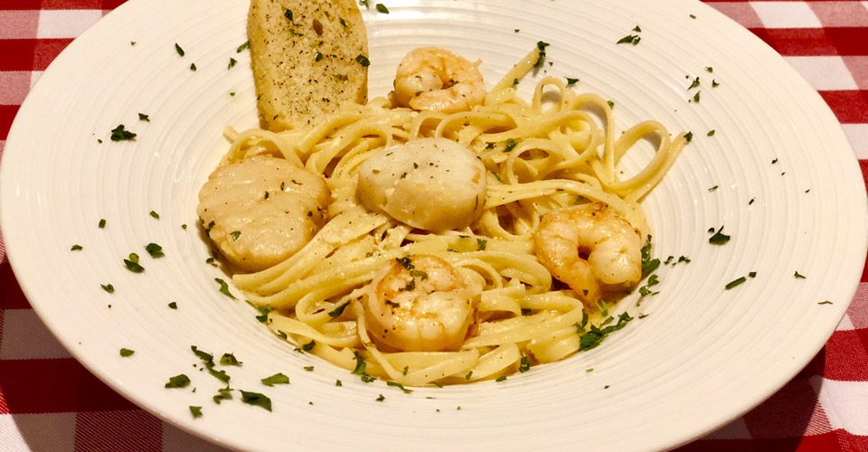 A white plate topped with pasta and shrimp.