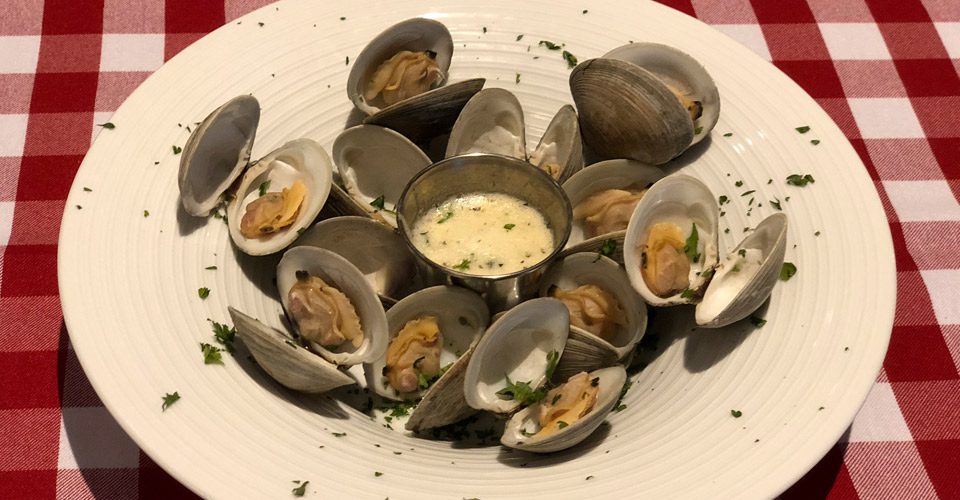 A plate of clams with dipping sauce on the side.