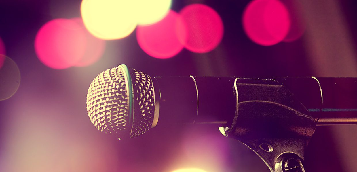 A microphone is on the stage with lights in the background.