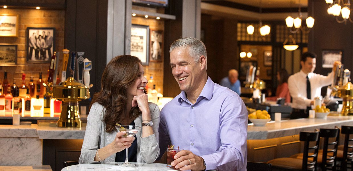 A man and woman sitting at a table with drinks.