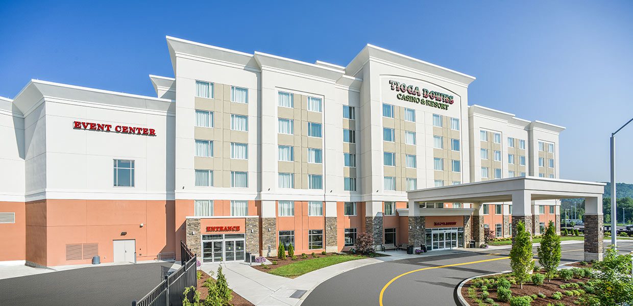 A hotel with a parking lot and trees in the background.