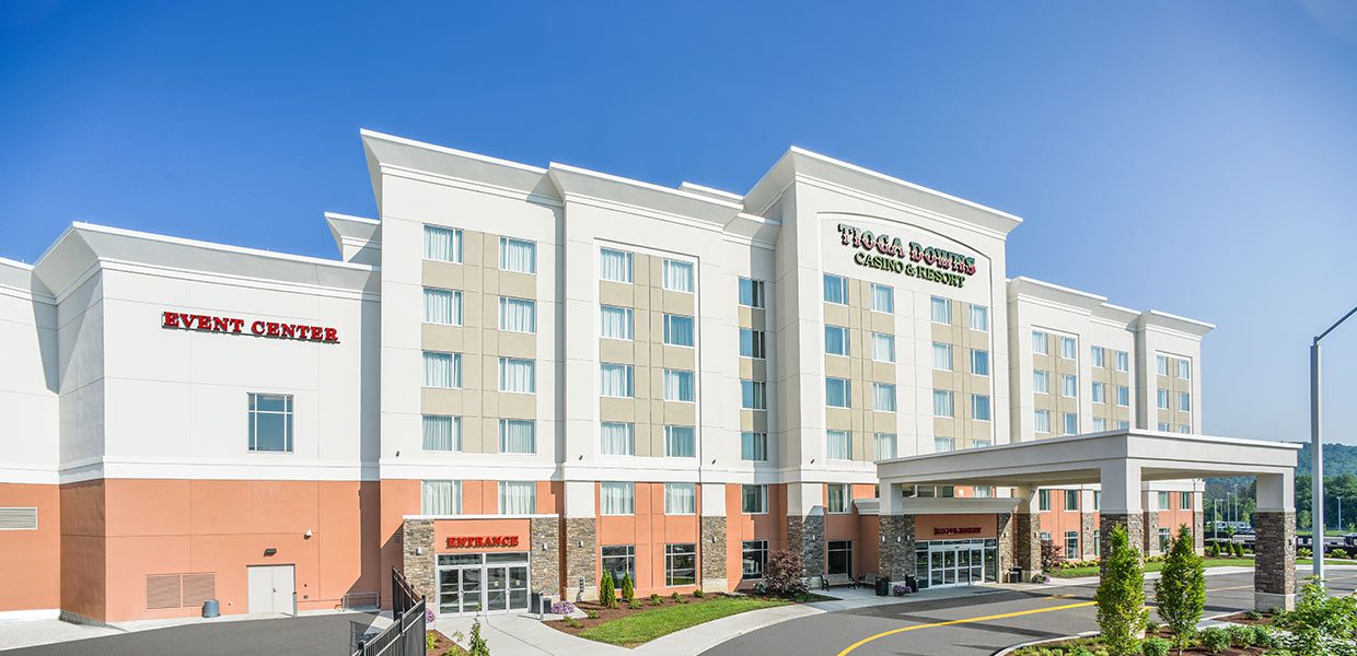 A hotel with a parking lot and trees in the background.