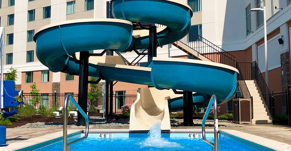 A pool with water slides and stairs going up.