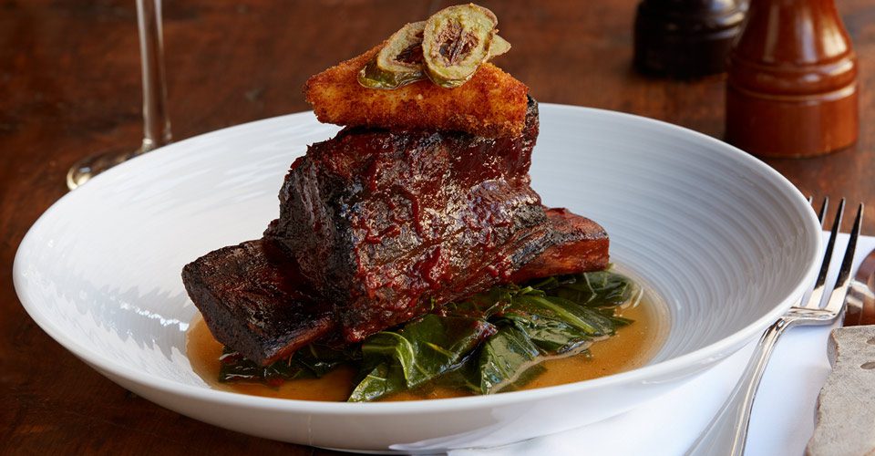 A plate of food with meat and greens on it.